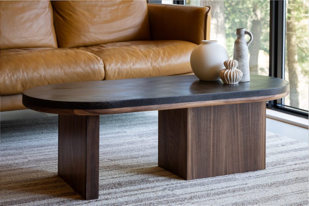 Oval pill-shaped coffee table with coffee shell finish and walnut wood base styled with ceramic accessories